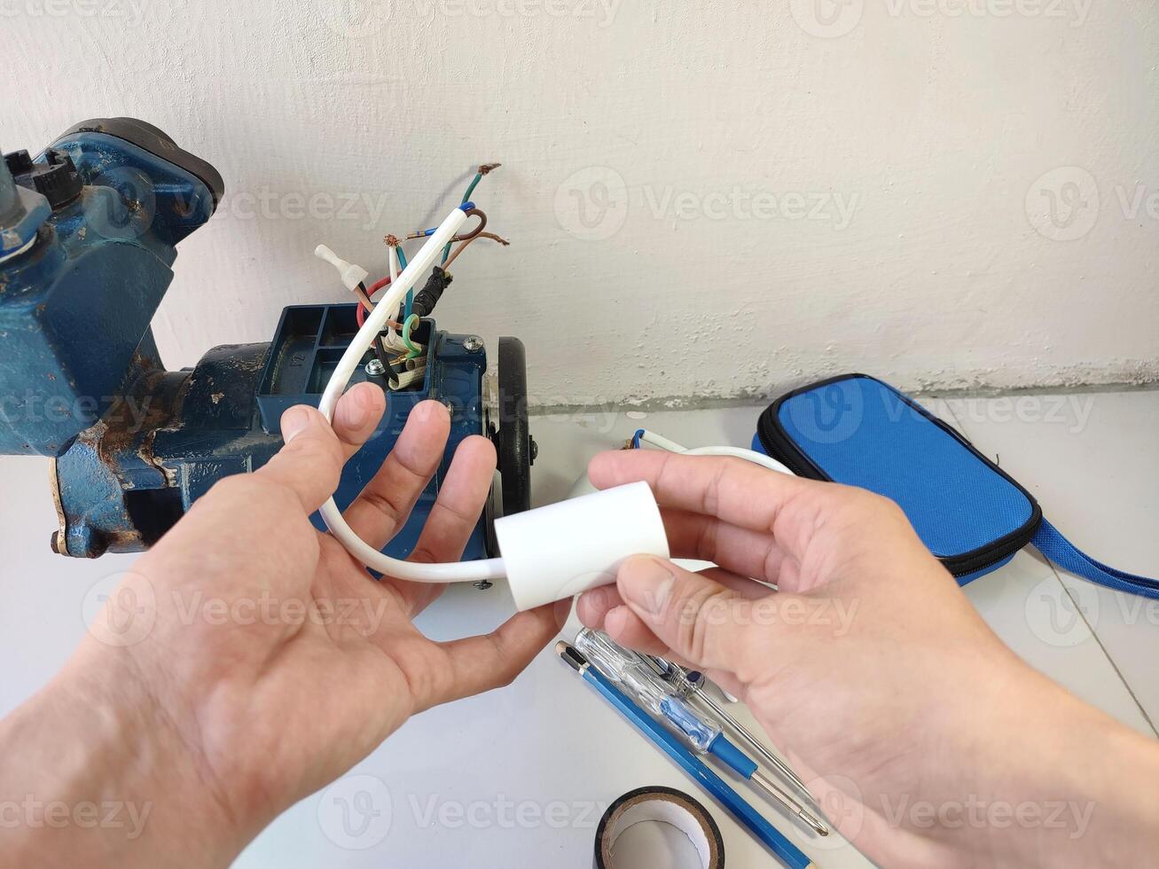 Hand holding and checking electric motor capacitor or Single phase motor photo