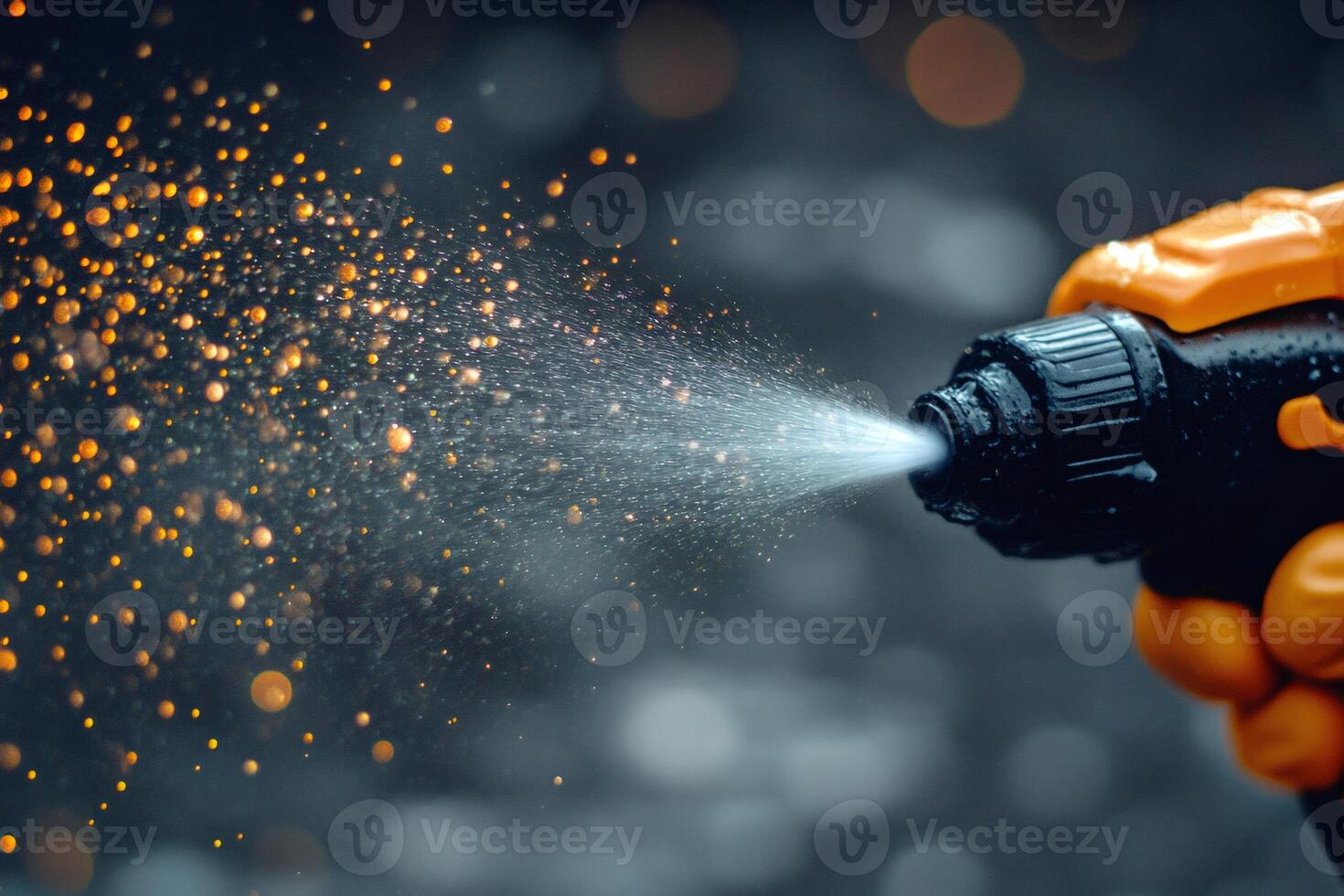 Gardener spraying water on plants with orange sprayer in garden photo