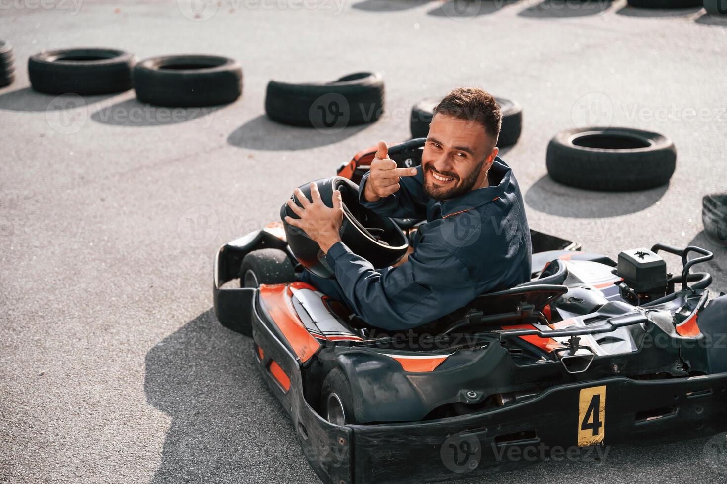 Looks behind ,,while riding. Man is outdoors, kart racing conception photo