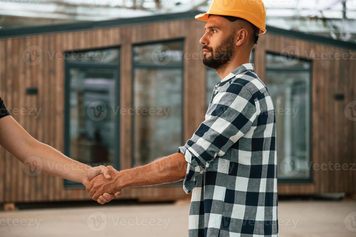 Close up view, doing handshake. Two workers are in the industrial wooden warehouse photo
