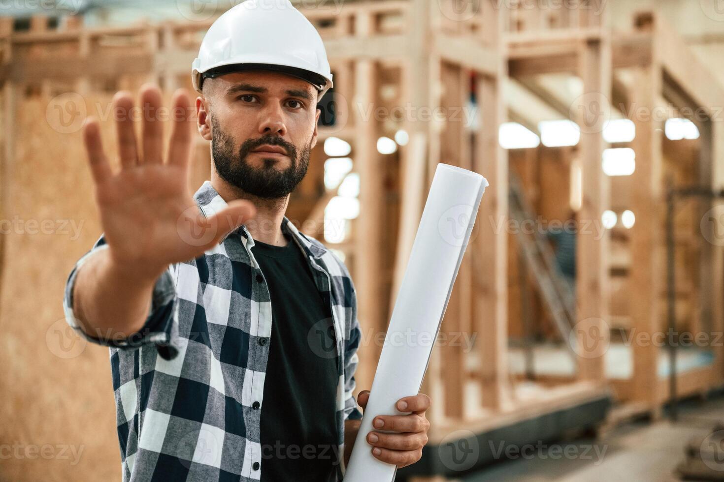 Stop hand gesture,, no trespassing. Industrial worker in wooden warehouse photo