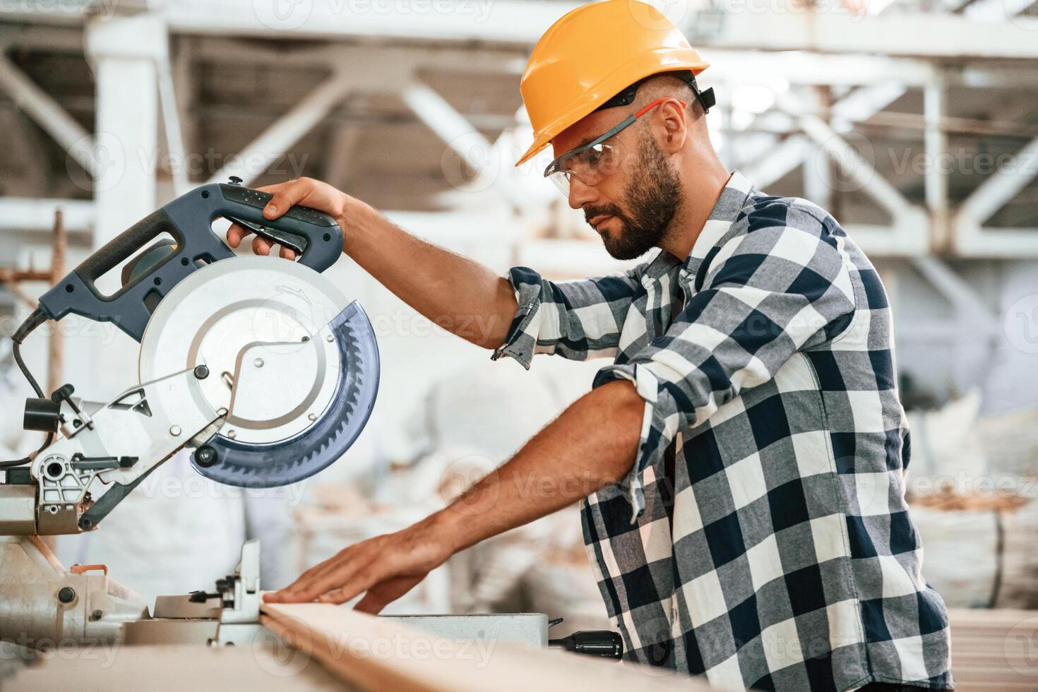 By the table,,, using blade, cutting the fresh wood. Industrial worker in warehouse photo