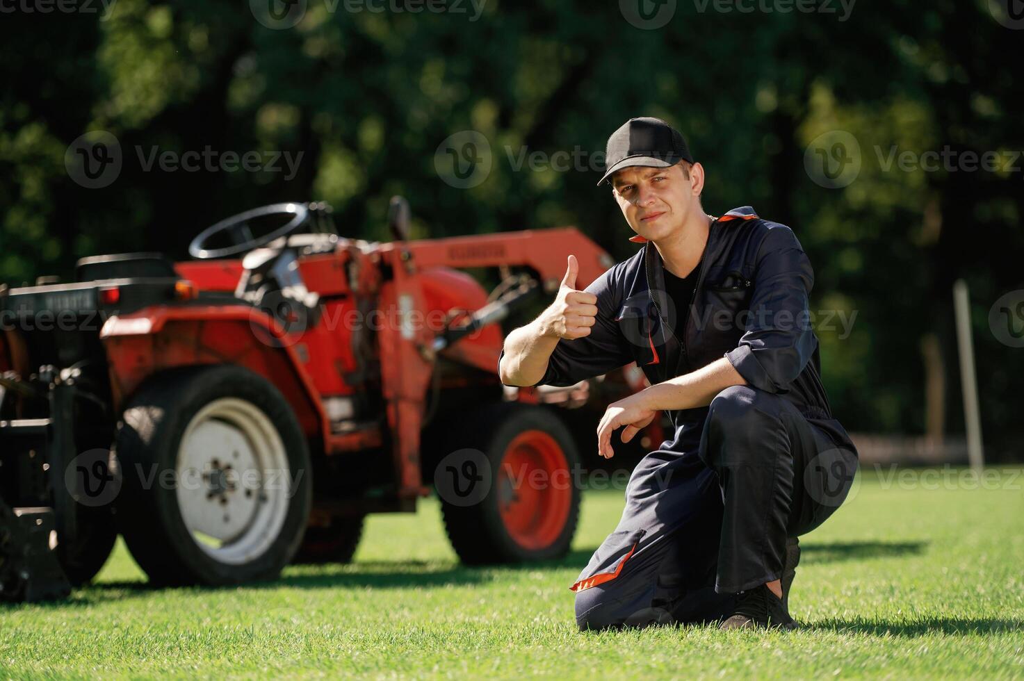Sitting,, with, thumb ,up. Man is with utility tractor with grass cutter and aerator equipment on the field photo