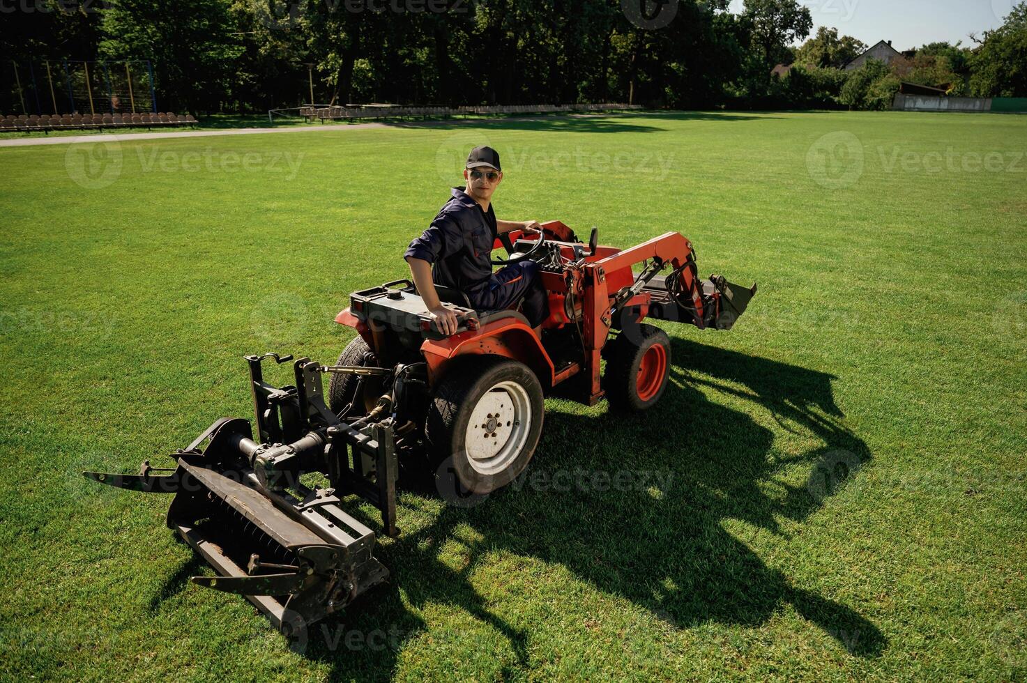 Loan, work. Man, is with utility tractor with grass cutter and aerator equipment on the field photo
