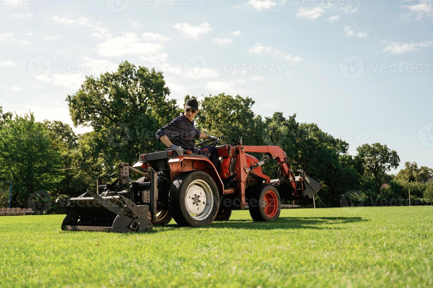Loan work... Man is with utility tractor with grass cutter and aerator equipment on the field photo