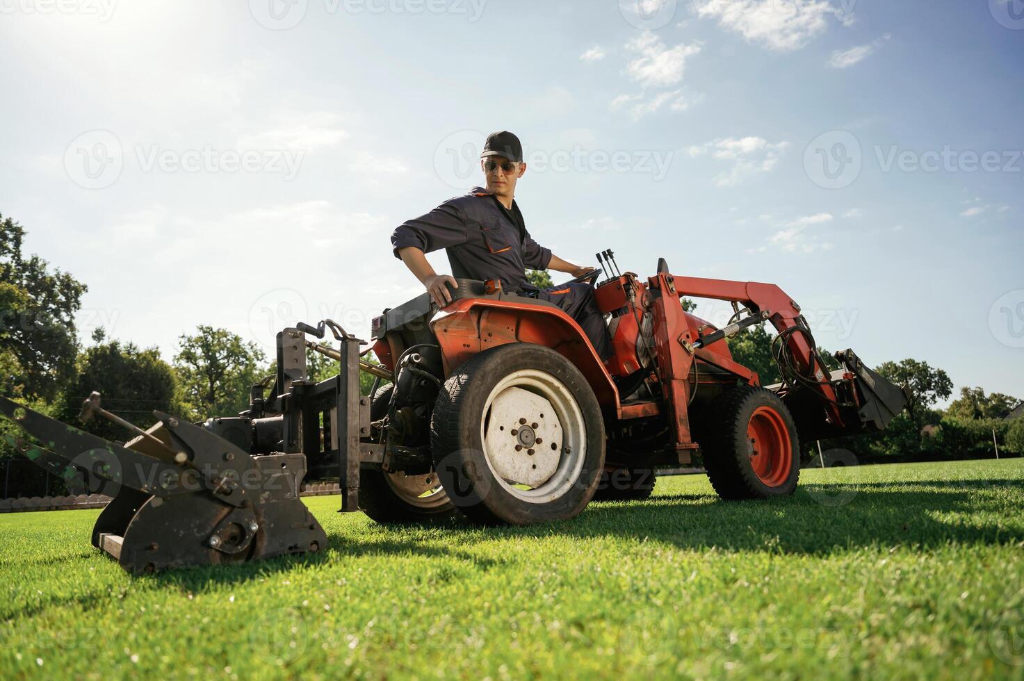 Loan ,work. Man is with utility tractor with grass cutter and aerator equipment on the field photo