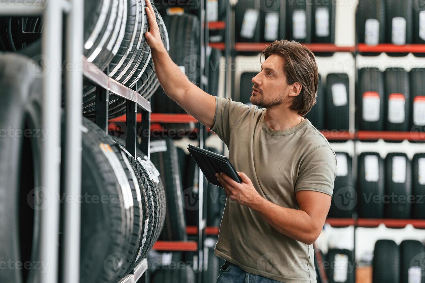 Digital tablet in hands. Man is ,in, the,, tire fitting car service photo