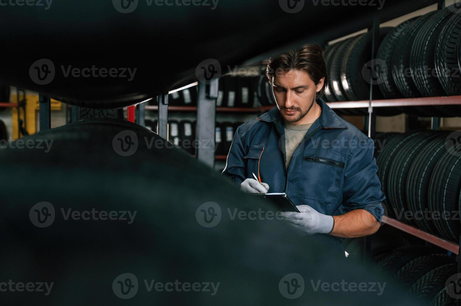 Work, in,, progress, manager, is in warehouse. Man is in the tire fitting car service photo