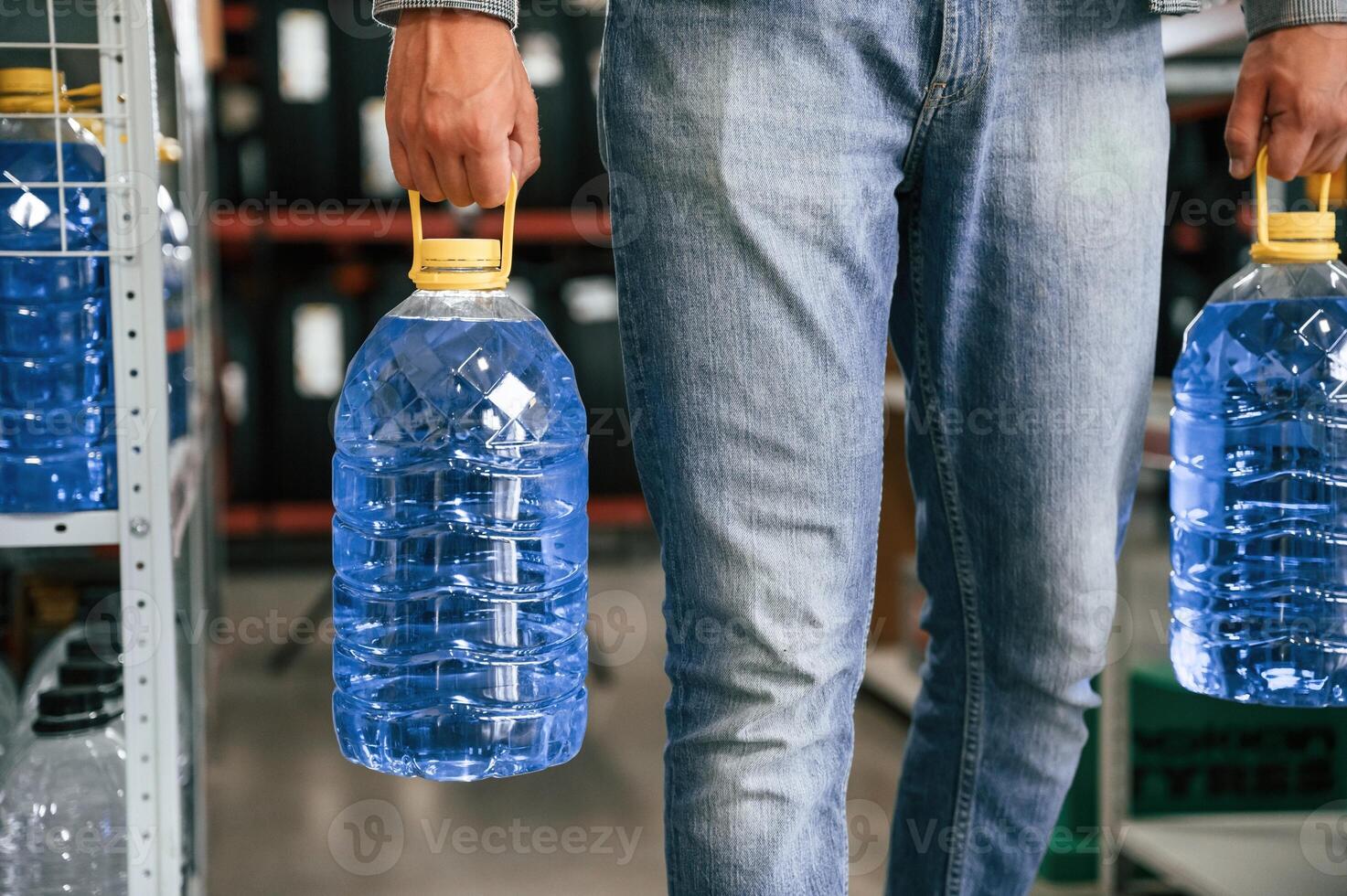 Close up view of man ,that is holding bottles of water, walking in the shop photo