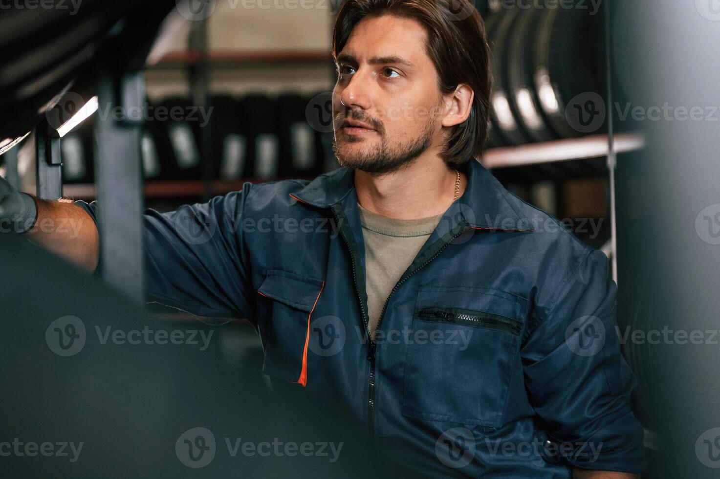 In ,professional uniform. Man,, is ,in the tire fitting car service photo