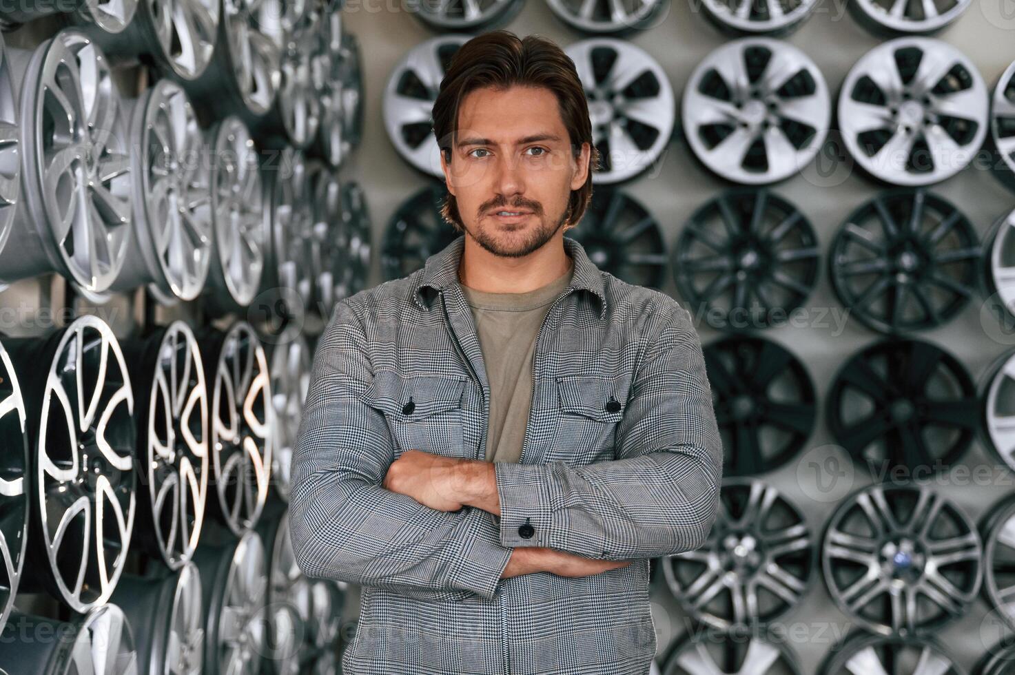 Many, of the disks on walls. Man is in the tire fitting car service photo