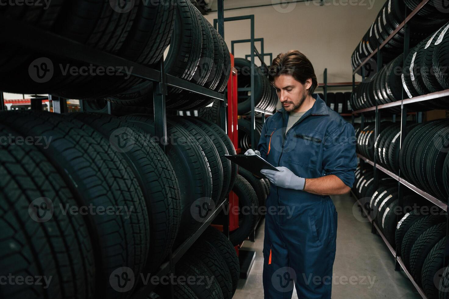 Holding, black notepad... Man is in the tire fitting car service photo