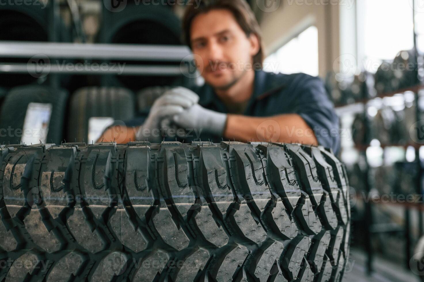 Professional worker is, with wheel. Man is in the tire fitting car service photo