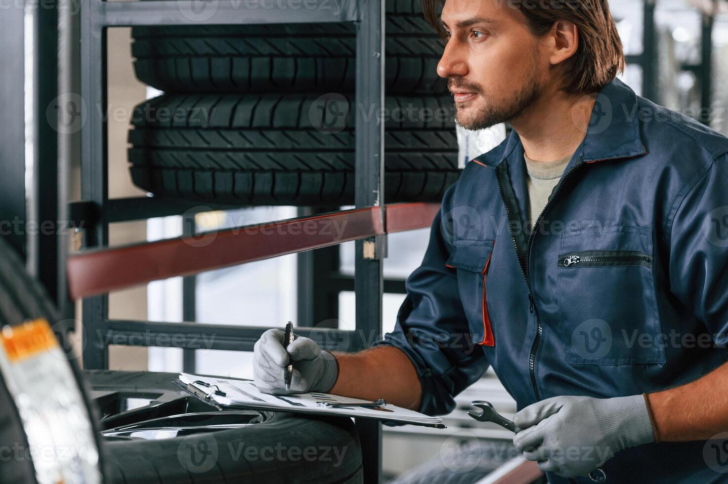 Writing, the data into ,notepad. Man is in the tire fitting car service photo