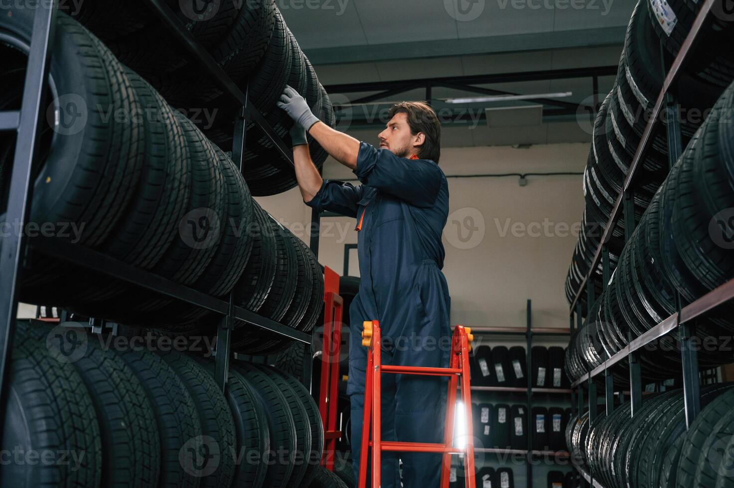 On, the ladder. Man is in the tire fitting car service photo