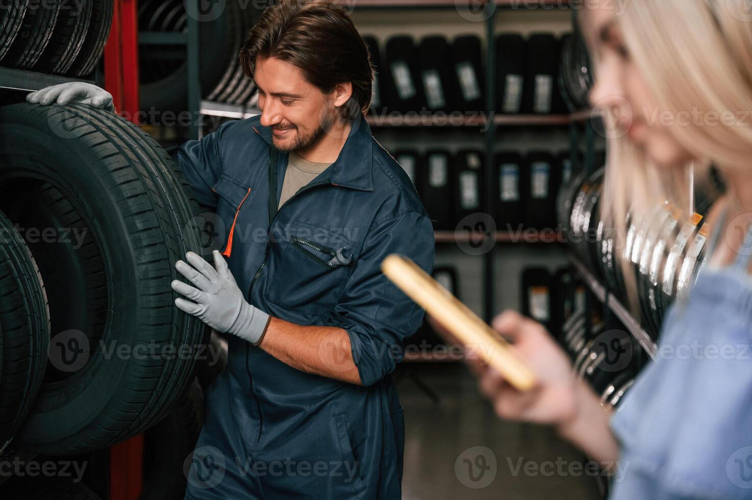 Giving the advice.. Woman is in the tire fitting auto shop with worker photo