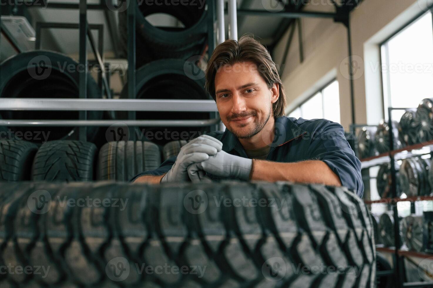 View, from the front, guy with a tire. Man is in the tire fitting car service photo