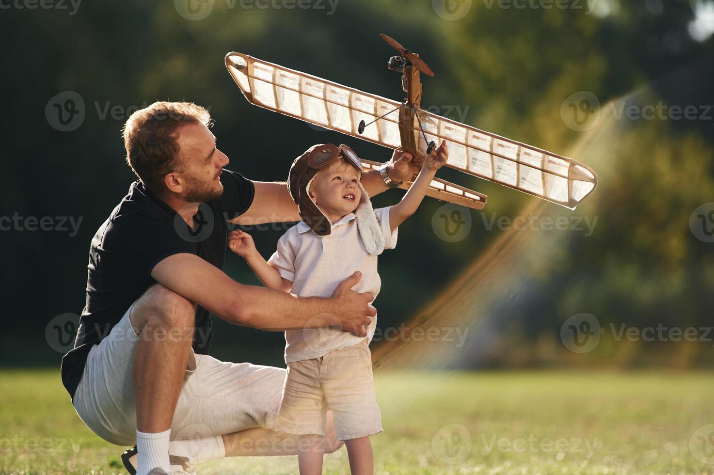 Weekend, activities. Father and son are,, on the field together with toy plane photo