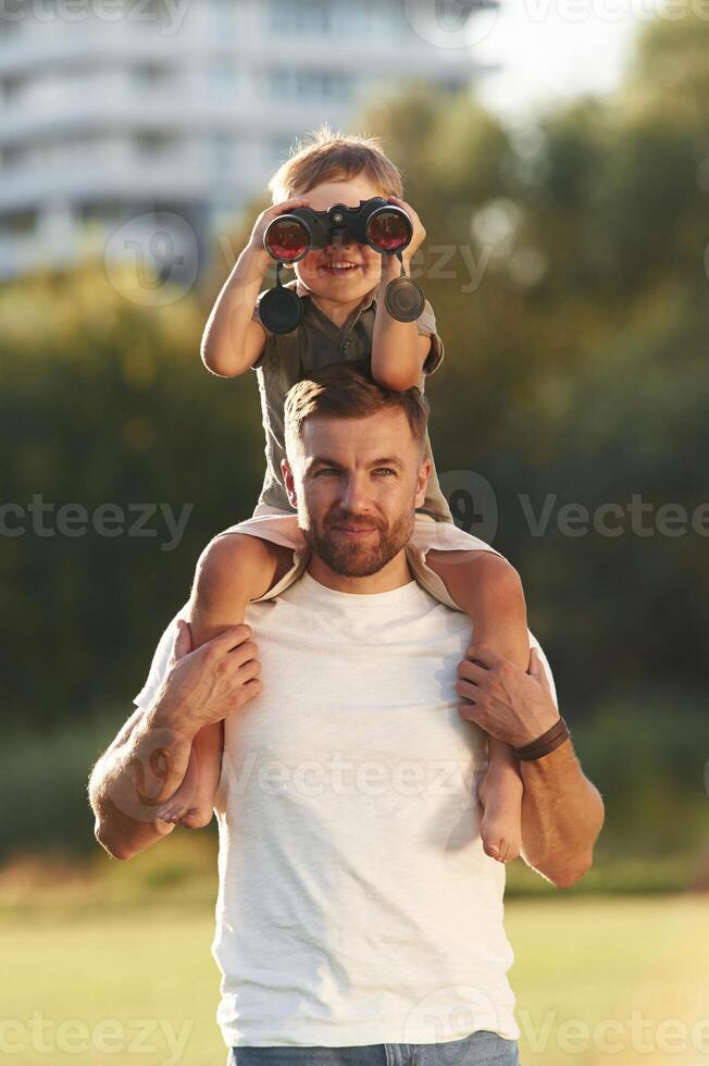 Looking through ,,,the binocular. Father and son are together on the field photo
