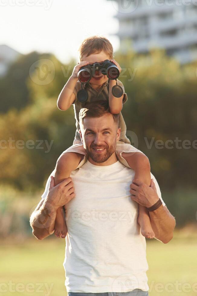Binocular in hands., Father and son are together on the field photo