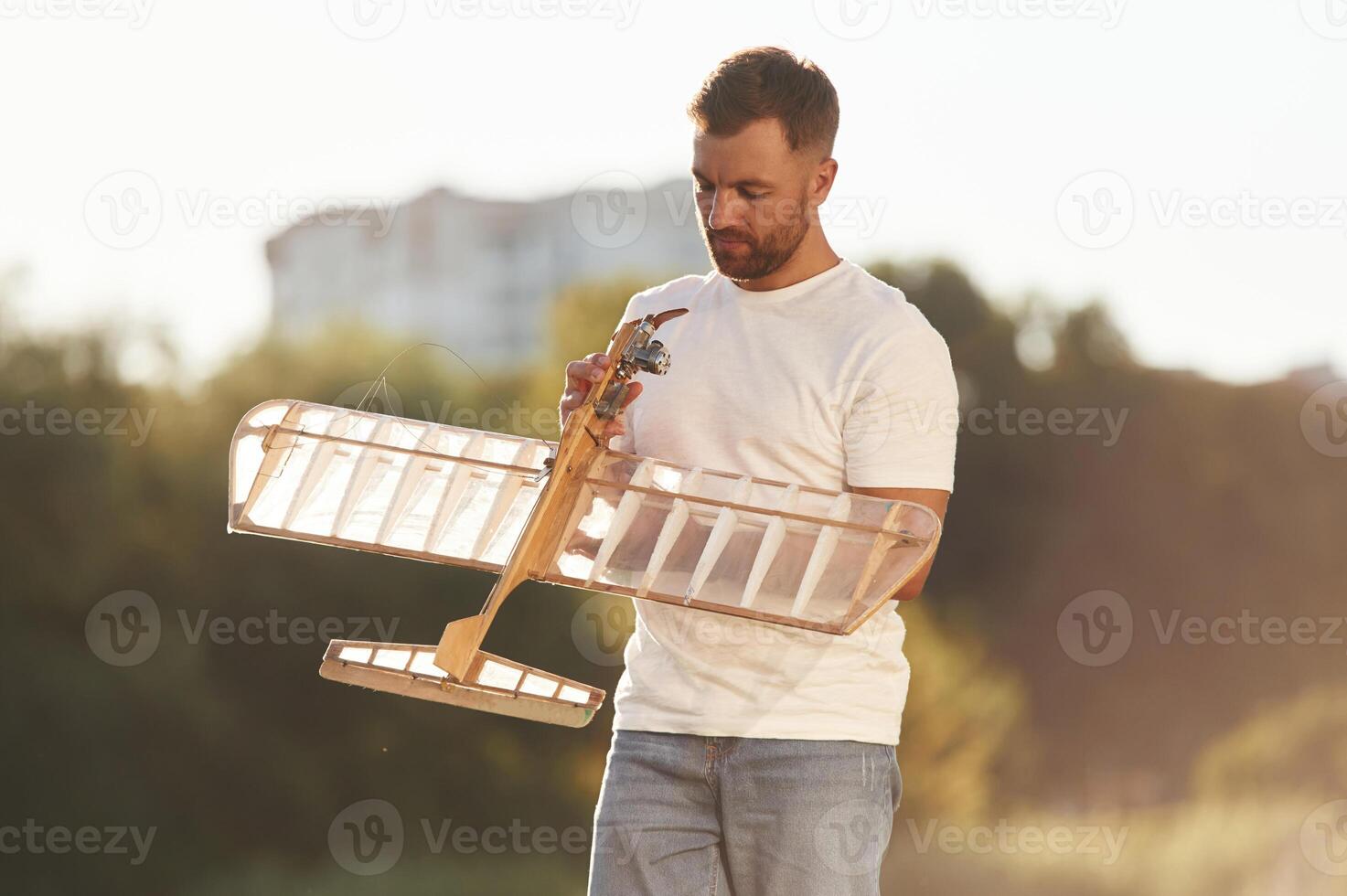 In casual ,clothes... Man is on the field fixing the toy plane photo
