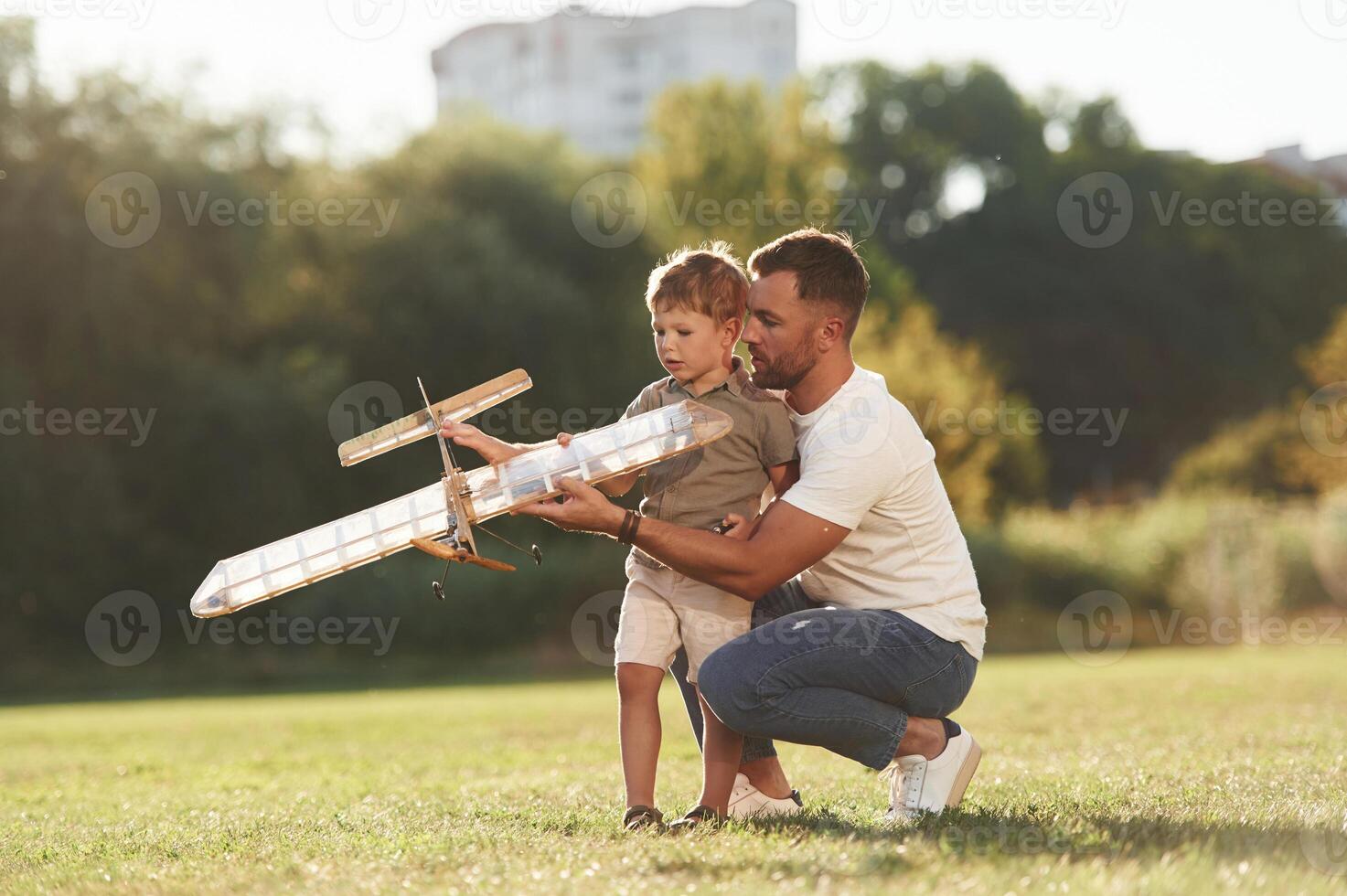 Joy, fun, weekend, activities. Father, and ,son are on the field together with toy plane photo