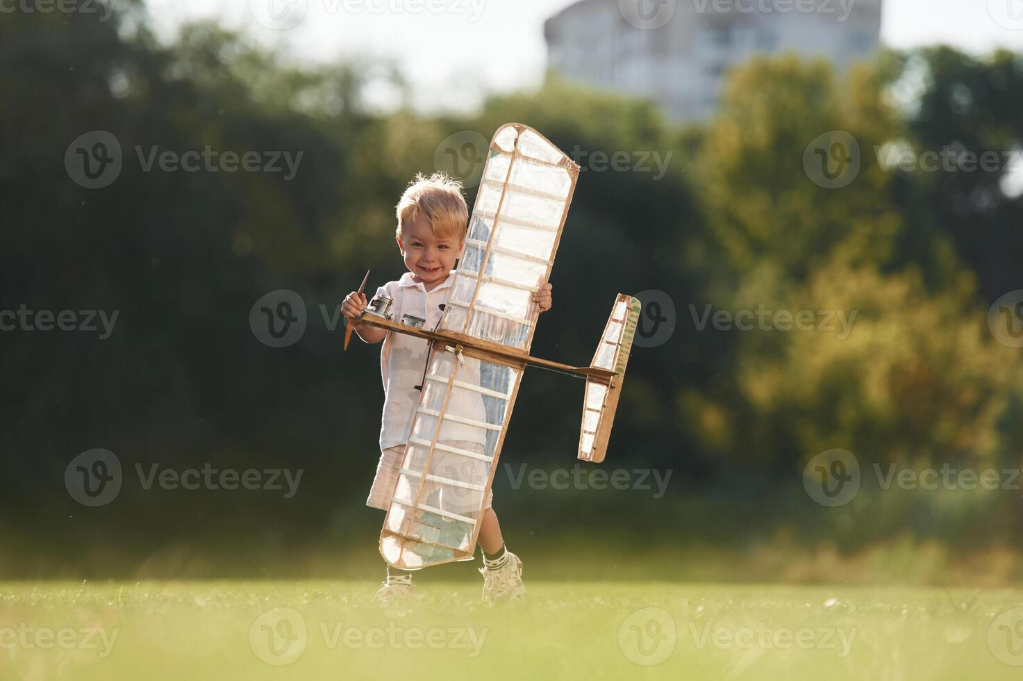 Cute ,little, boy is playing with toy plane on the field photo