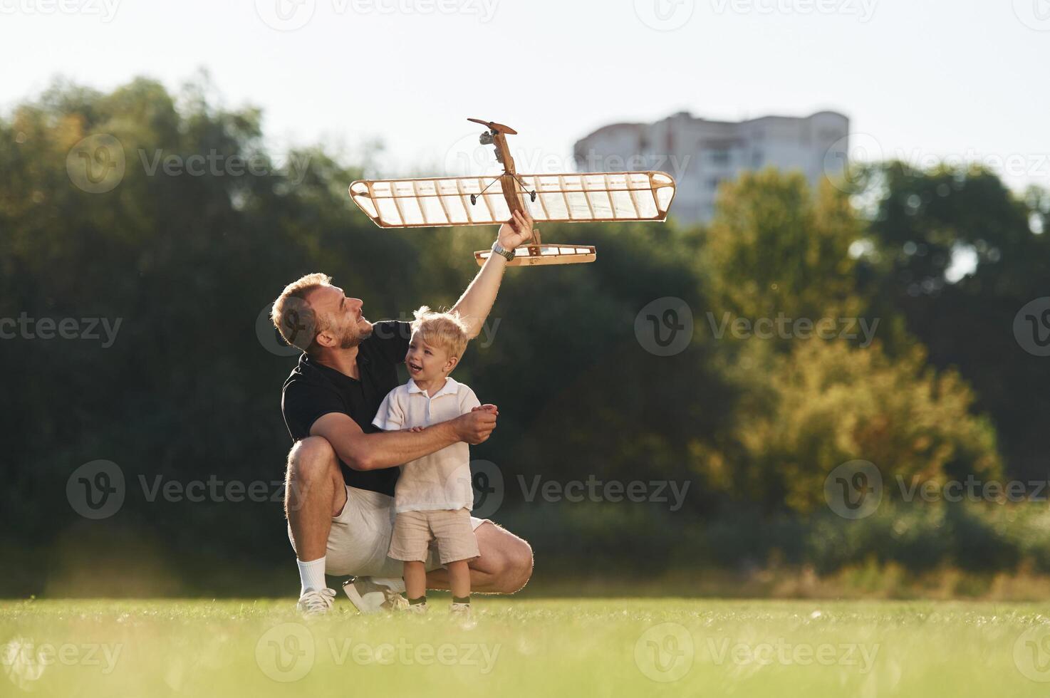 Having fun, sitting., Father and son are on the field together with toy plane photo