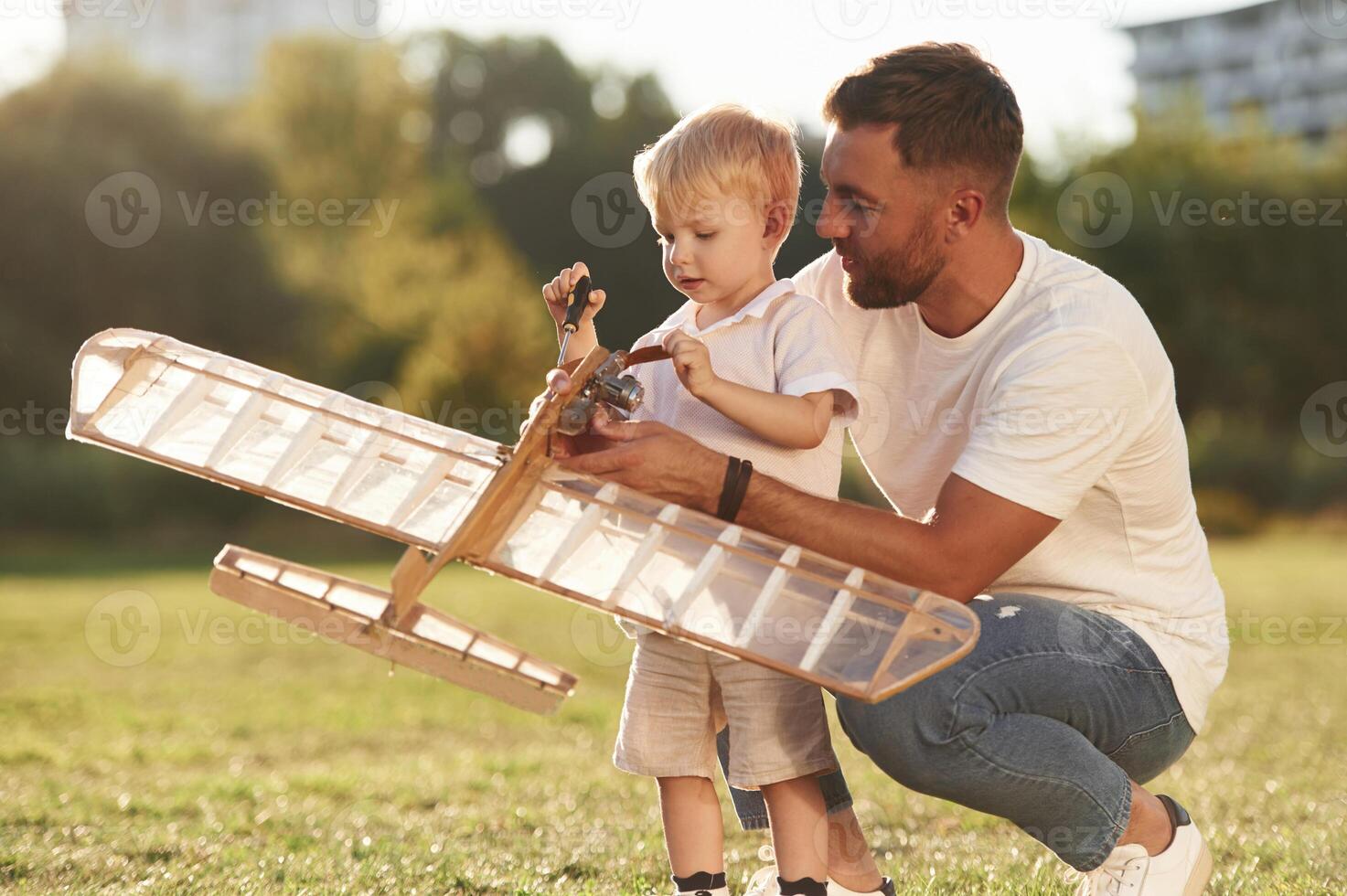 Teaching, the kid ,how to fix it. Father and son are on the field together with toy plane photo