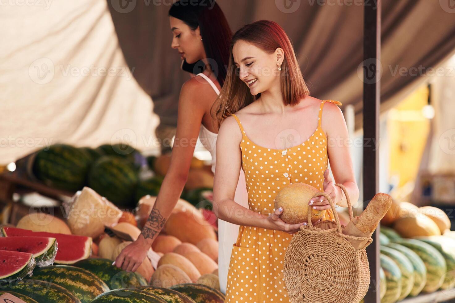 Friend is holding the melon., Two women are together on the marker or bazaar photo