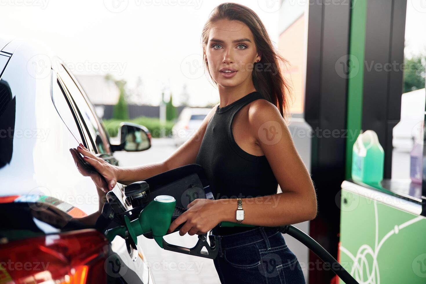 Refilling the vehicle. A young woman at ,a gas station with ,,her car photo