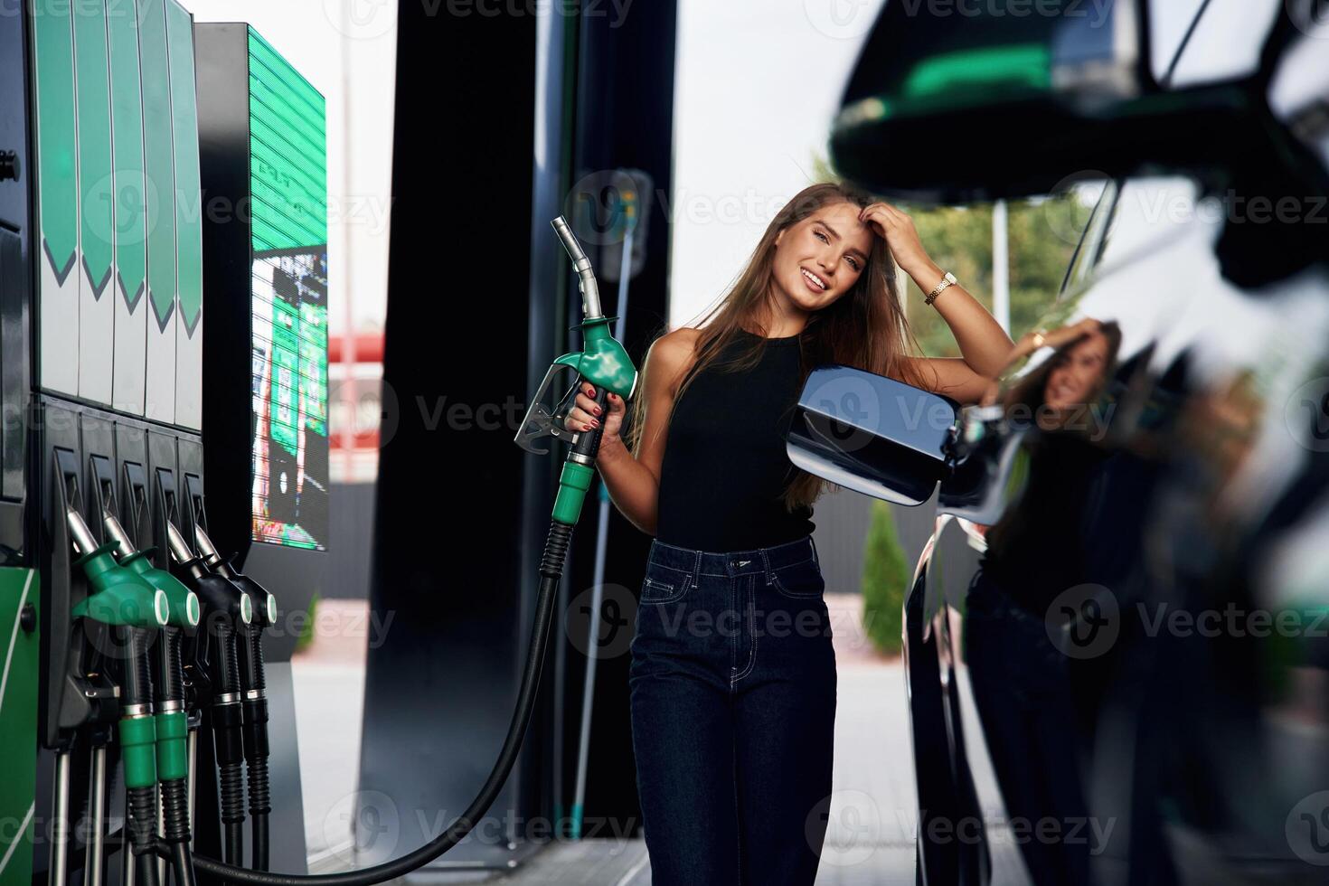 Ready to refill the automobile., A young woman at a gas station with her car photo