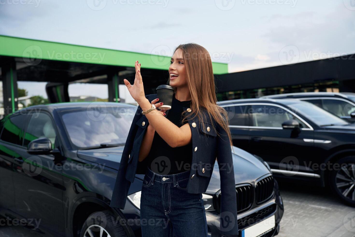 Hello, gesture. A young woman ,at a gas station with her car photo