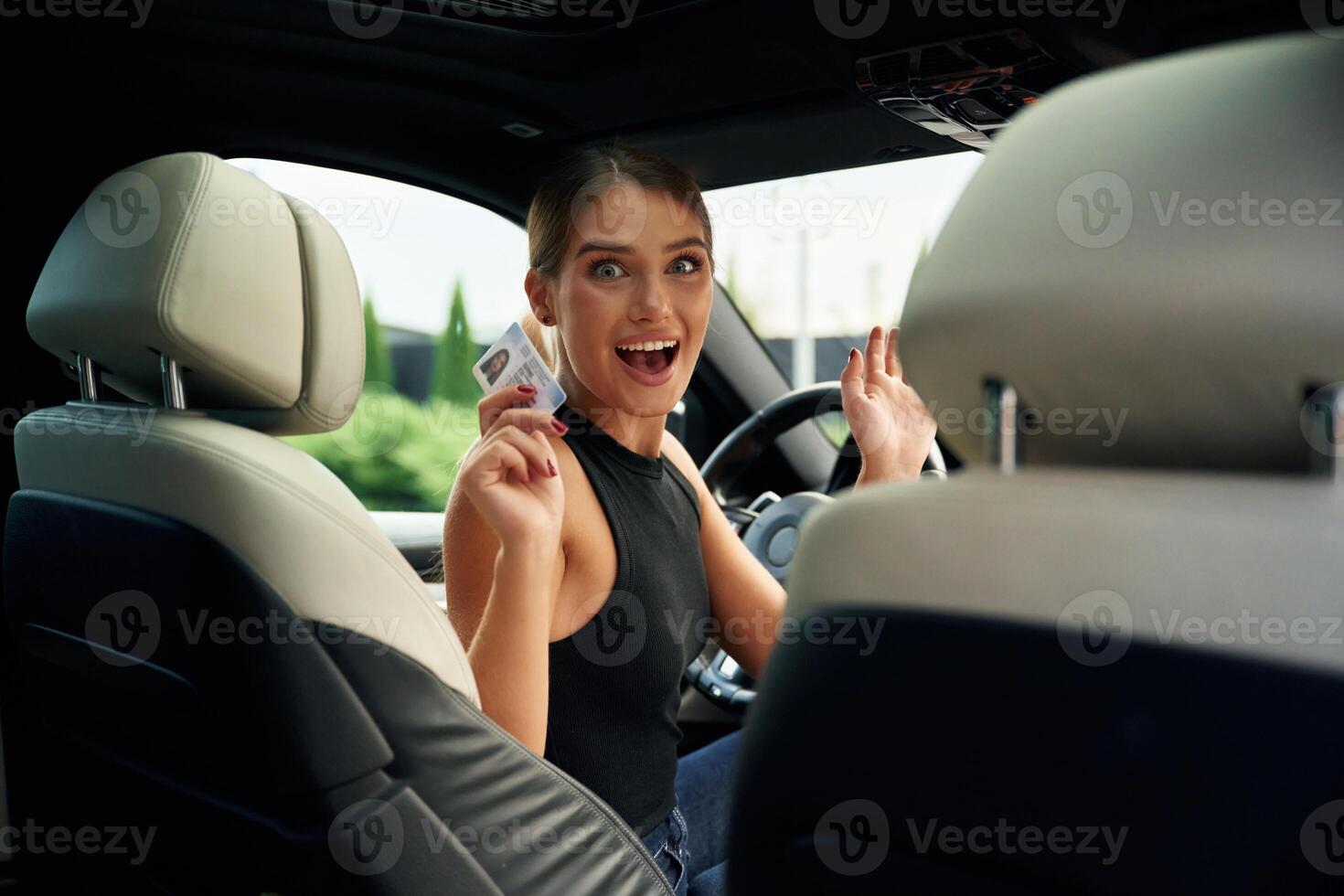 Showing off, with the driver's license. Woman is sitting in the car photo