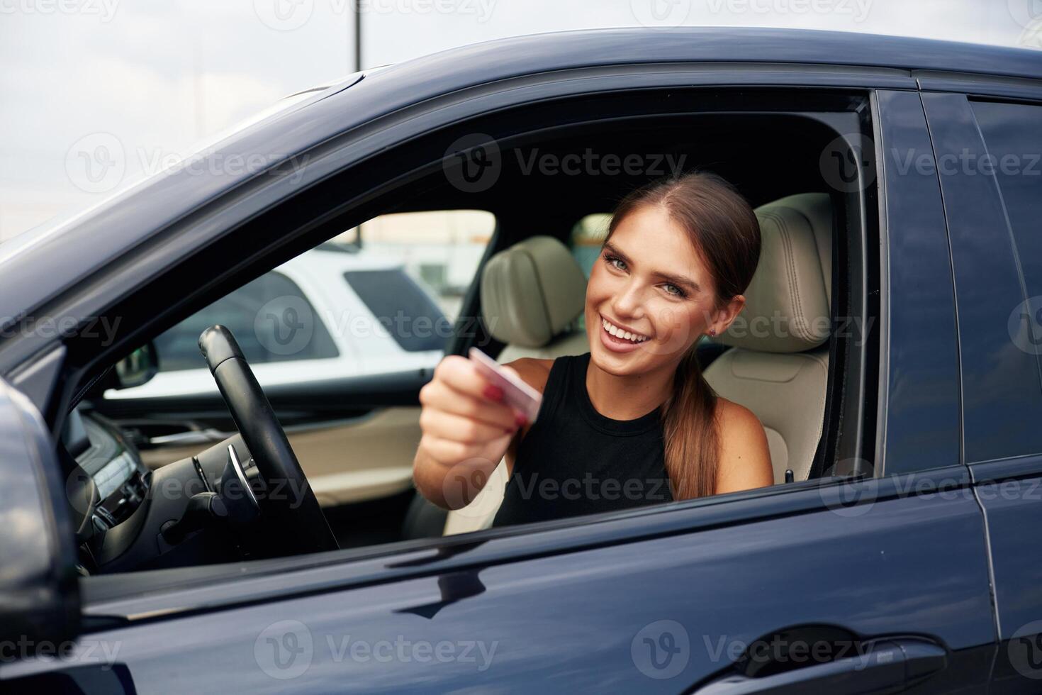 Showing ,off with the driver's license. Woman is sitting in the car photo