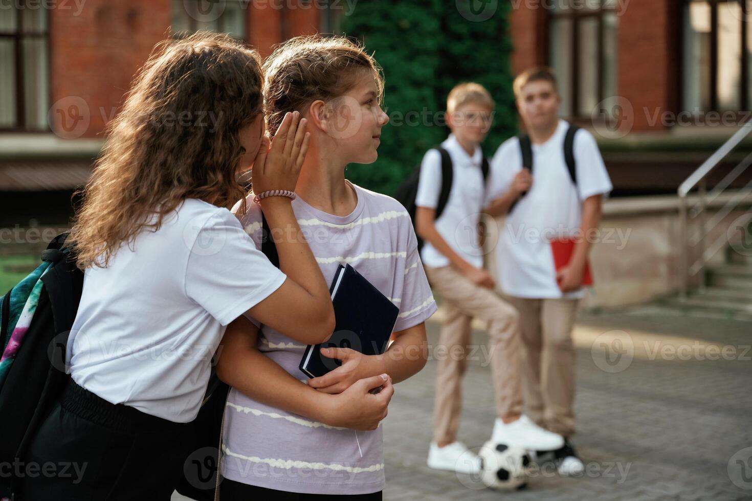Gossip about the ,,,,boys. Kids are near the school together, pupils photo