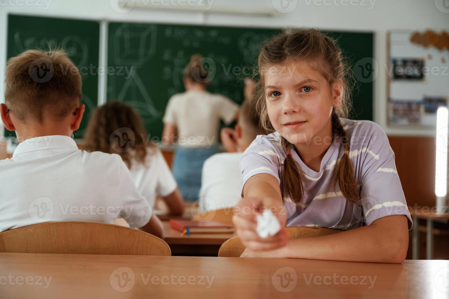 Girl ,is, gives a cheat sheet. Pupils, kids in the classroom together photo