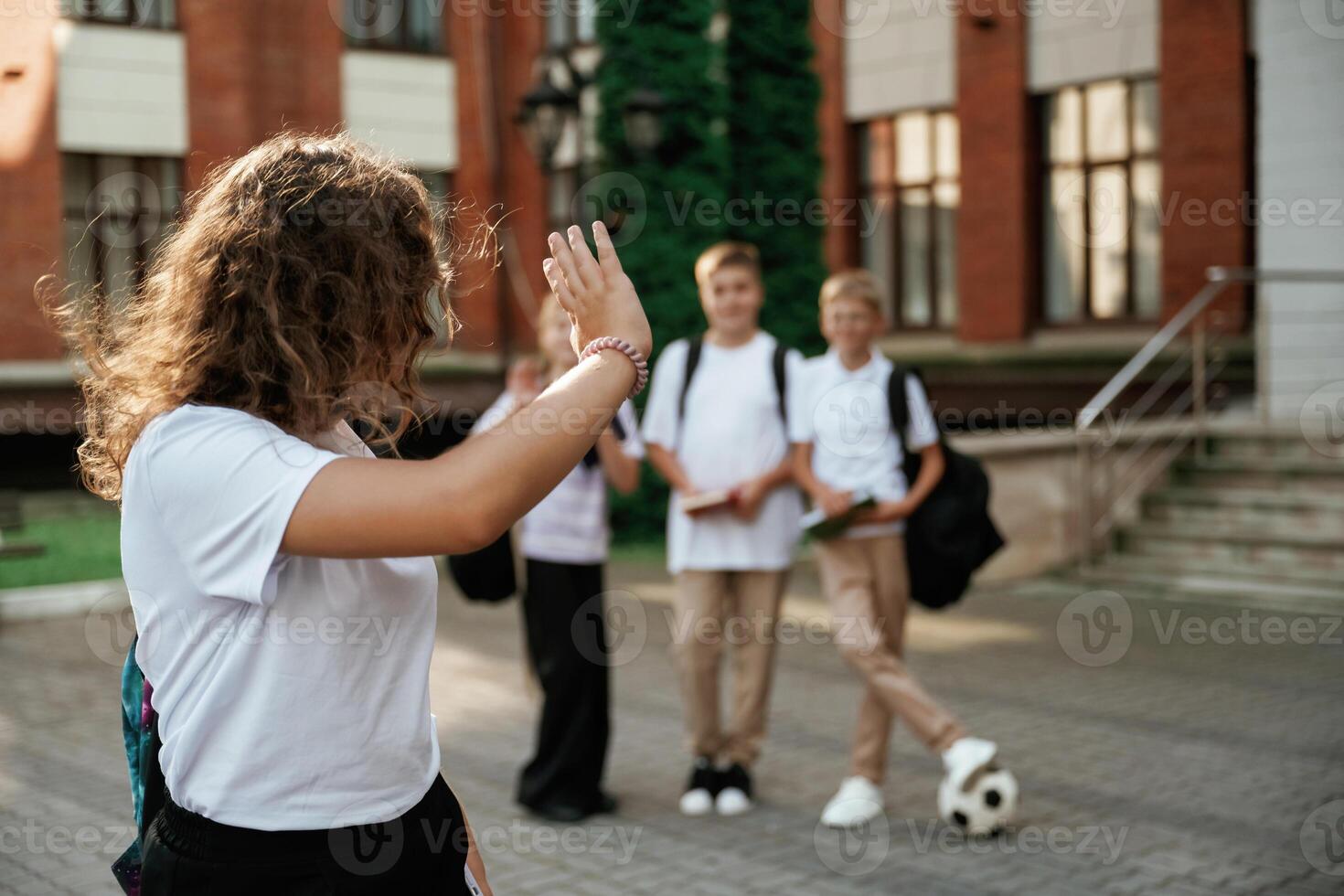 Standing, and posing. Kids are near the school together, pupils photo