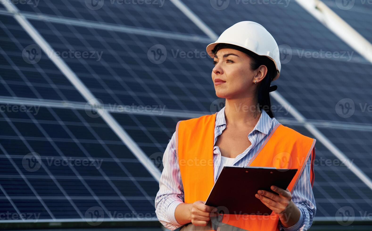 Notepad, in, hands. Female worker engineer in ,uniform is near solar panels.. photo