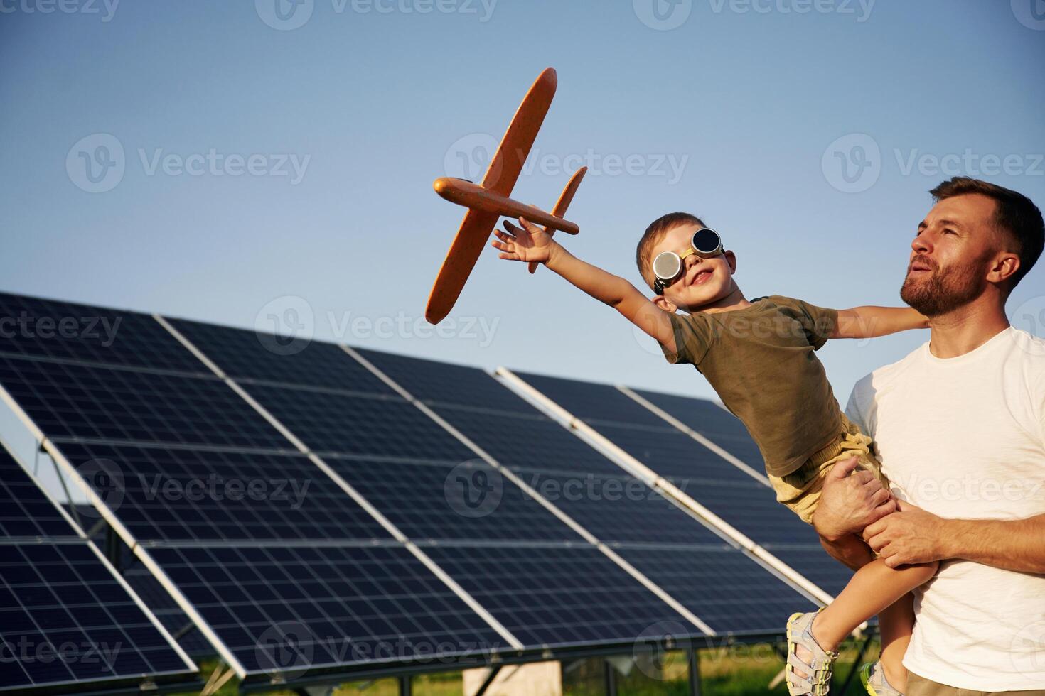 Aviator glasses and toy plane.. Father with his little son are together near the solar panels photo