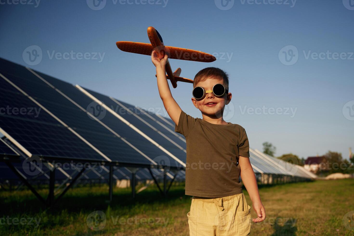 Time, to, fly. Aviator glasses and toy plane. Little boy is with solar panels outdoors photo
