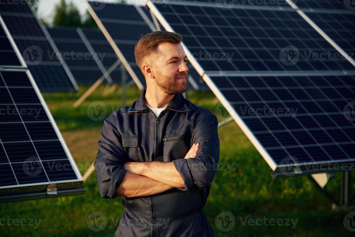 Portrait, standing with arms crossed,. Man is working with solar panels outdoors at daytime photo