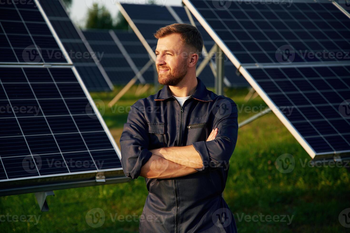 Portrait, standing with arms,,, crossed. Man is working with solar panels outdoors at daytime photo