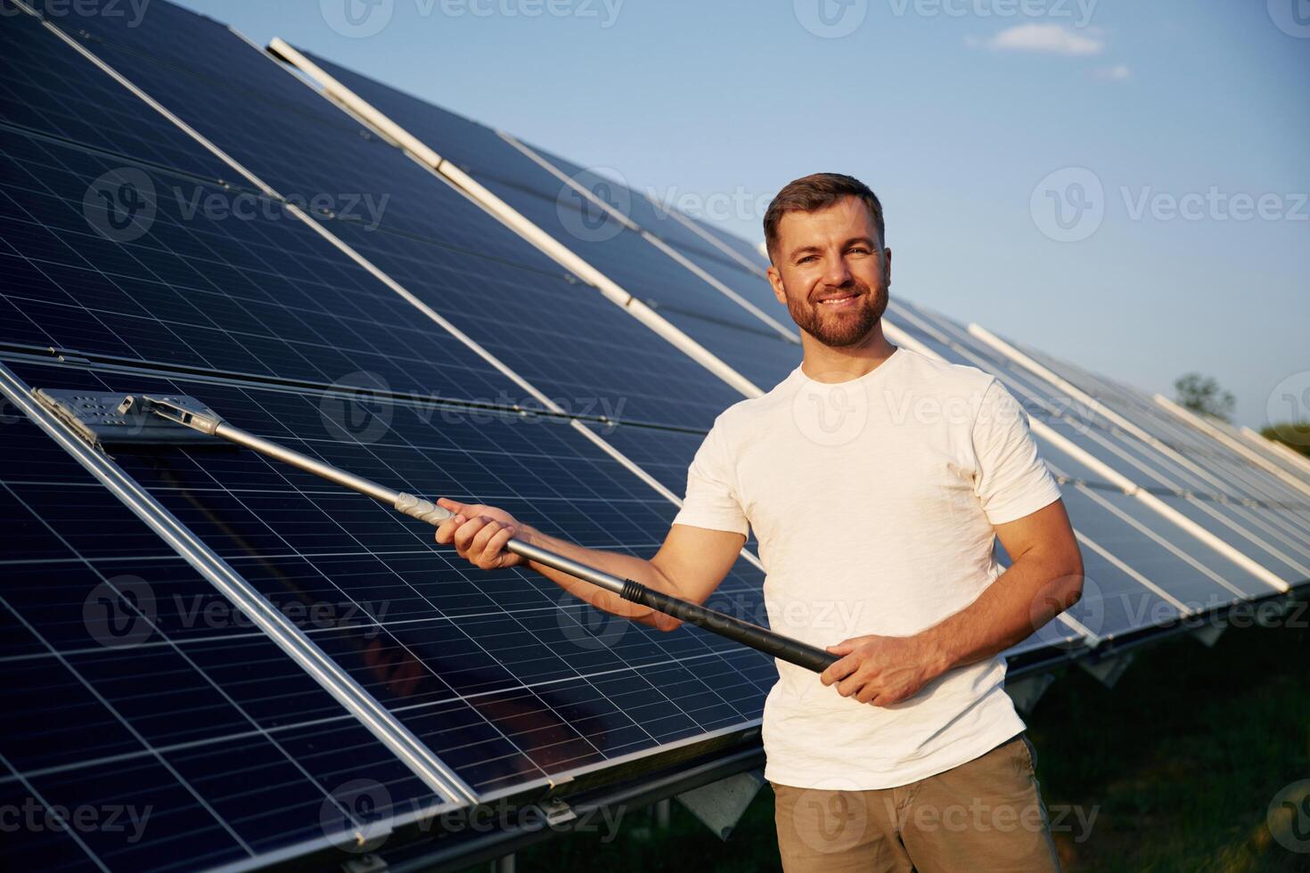 Mop,,, in ,hands. Man is working with solar panels outdoors at daytime photo