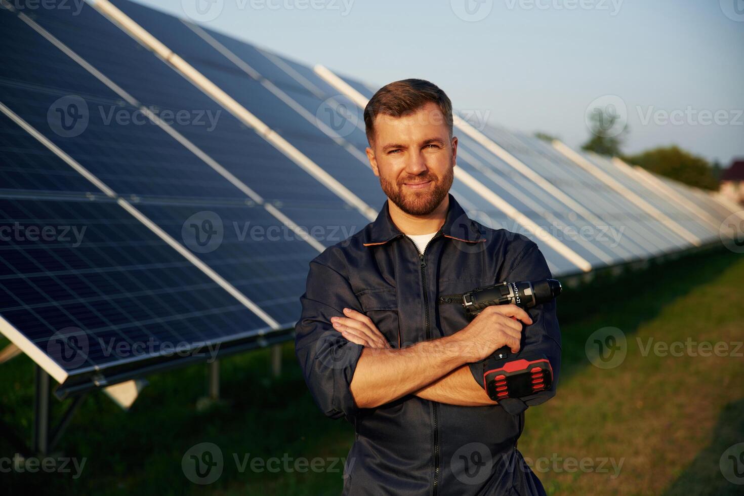 Taking a break, standing... Man is working with solar panels outdoors at daytime photo