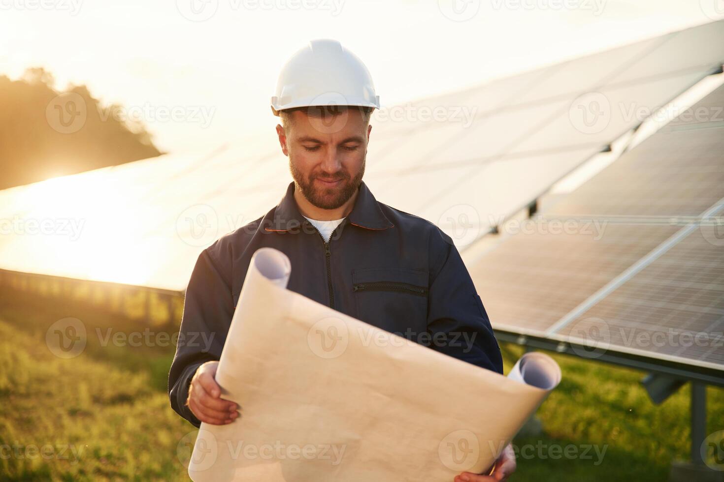Paper ,plan, in ,,hands. Man is working with solar panels outdoors at daytime photo