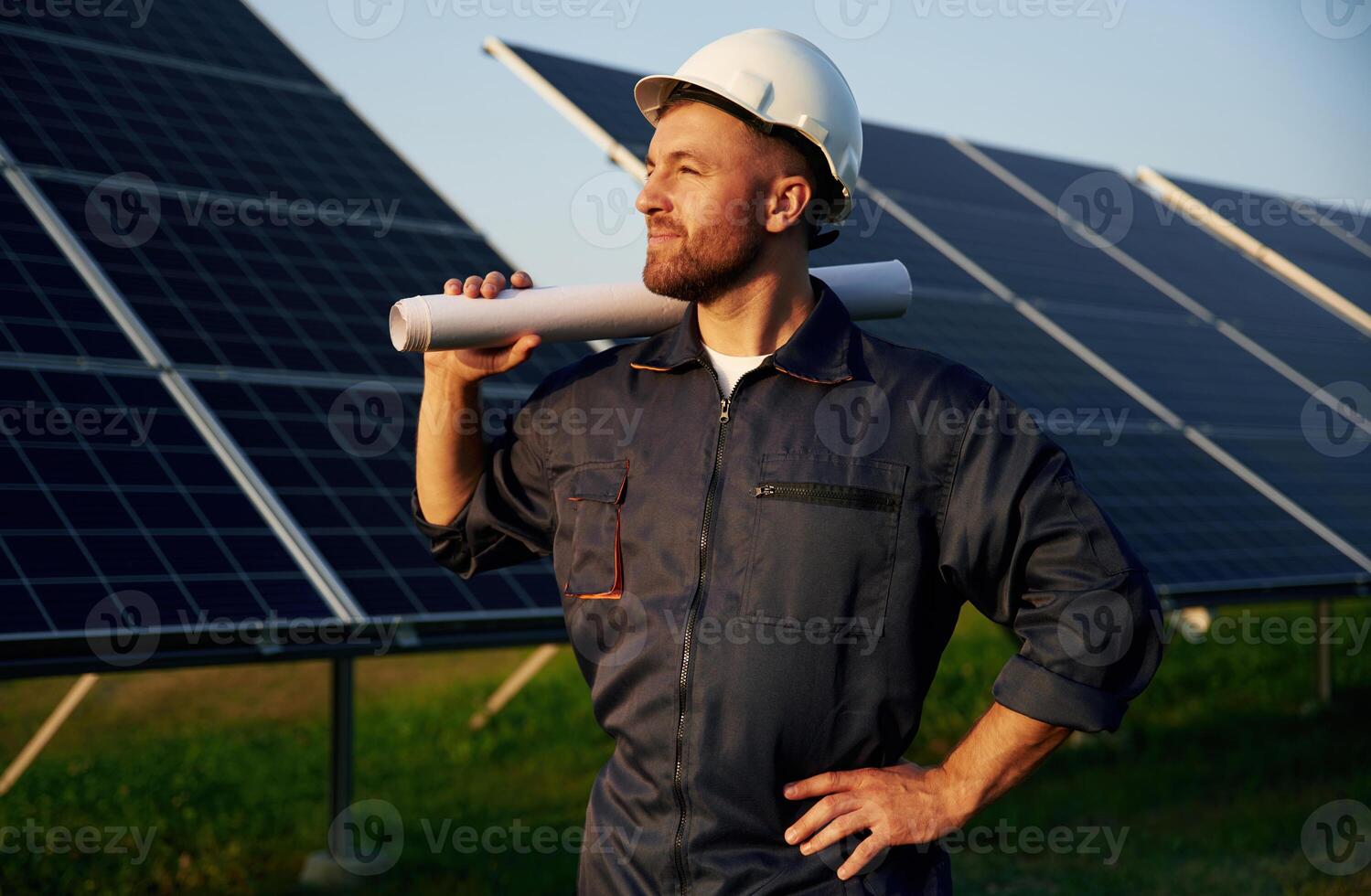 Taking a break, ,standing. Man is working with solar panels outdoors at daytime photo
