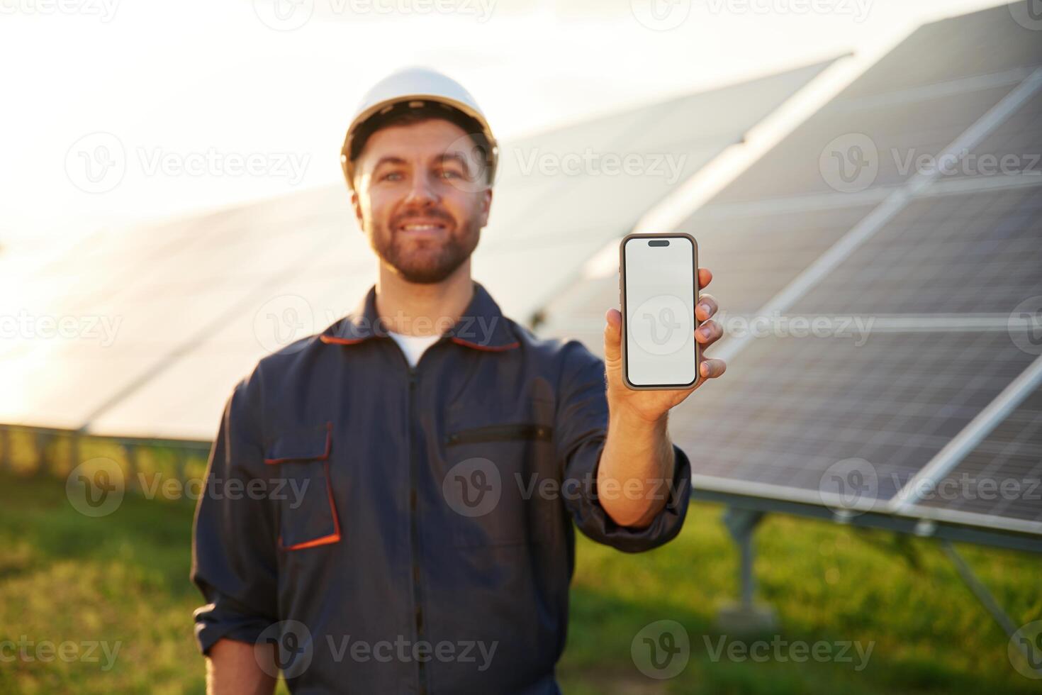 Smartphone with ,,copy space on it. Man is working with solar panels outdoors at daytime photo