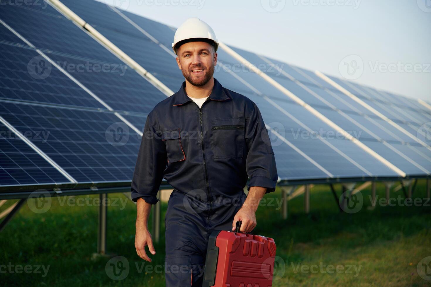 Red ,case, in hand. Man is working with solar panels outdoors at daytime photo