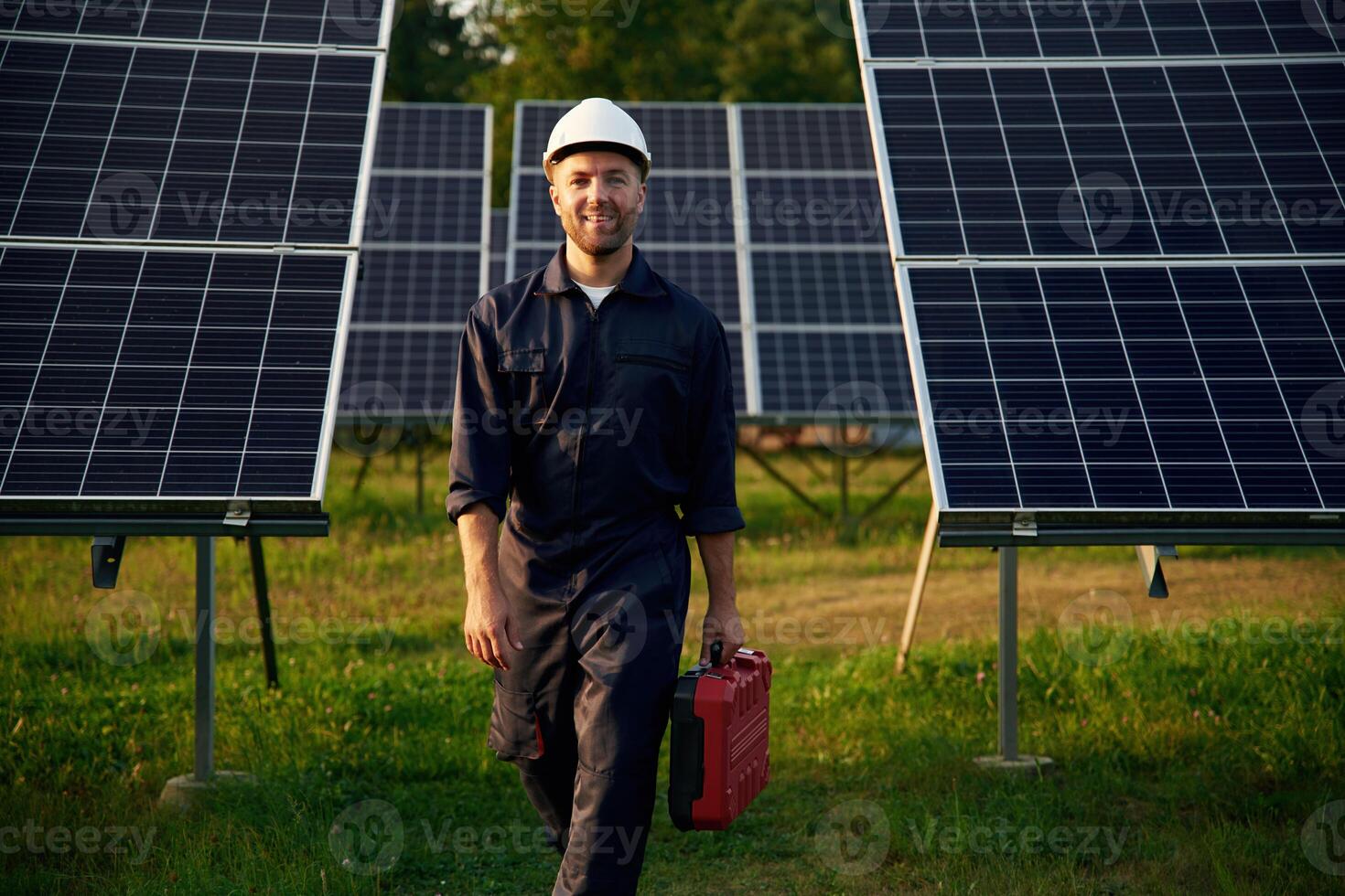 Red case, in hand. Man is working with solar panels outdoors at daytime photo